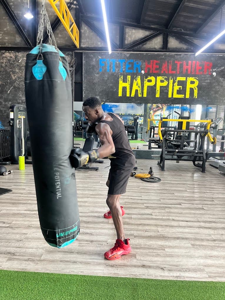 A member working the heavy bag under the Fitter Healthier Happier wall