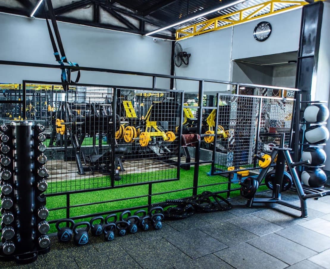 Dumbbells, kettlebells and battle ropes along the turf strip, plate-loaded machines behind
